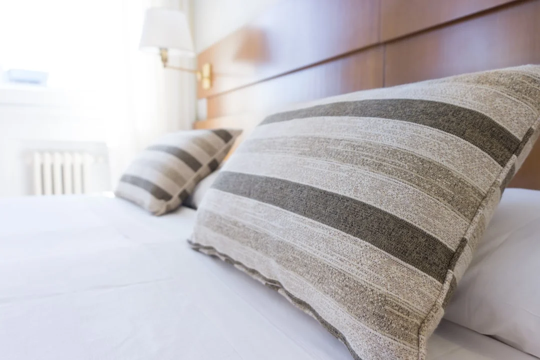 why-choose-us A hotel housekeeper neatly stacks fresh towels in a luxurious room setting.